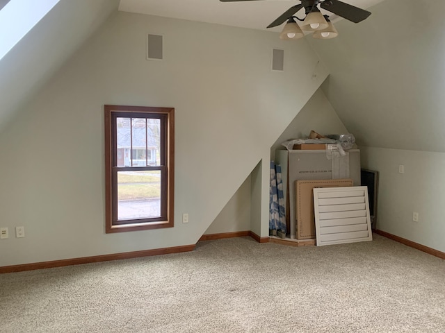 additional living space with ceiling fan, vaulted ceiling with skylight, and carpet flooring