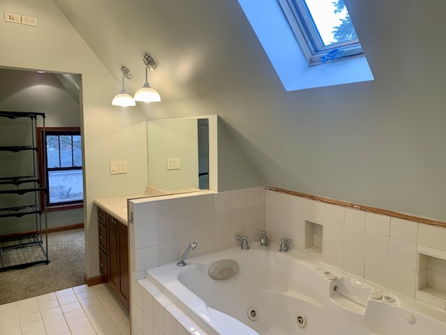 bathroom with tiled tub, lofted ceiling with skylight, tile patterned flooring, and vanity