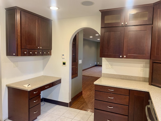 kitchen with light stone countertops, dishwasher, dark brown cabinets, and light tile patterned floors