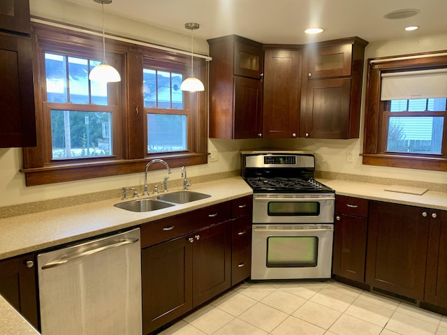 kitchen with decorative light fixtures, sink, light tile patterned floors, stainless steel appliances, and dark brown cabinets