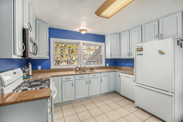 kitchen with sink, white appliances, a textured ceiling, and light tile patterned flooring