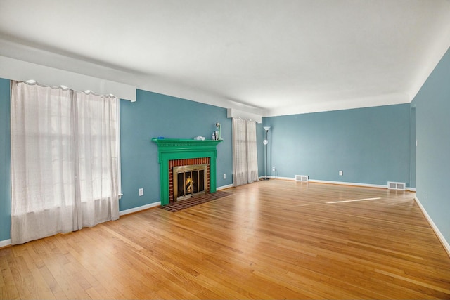 unfurnished living room with hardwood / wood-style floors and a brick fireplace