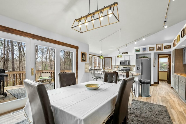 dining space with rail lighting and light hardwood / wood-style floors