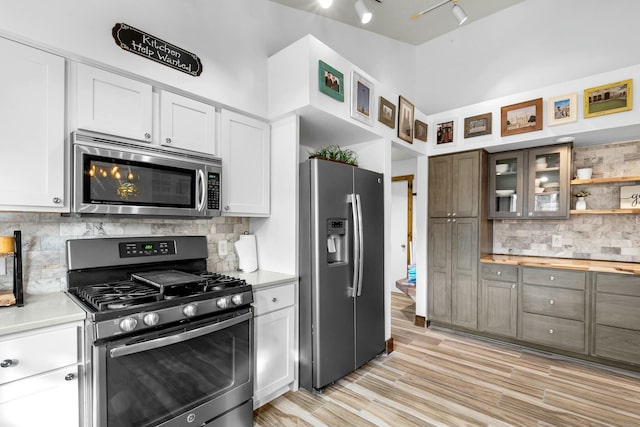 kitchen with white cabinetry, stainless steel appliances, tasteful backsplash, and light hardwood / wood-style flooring