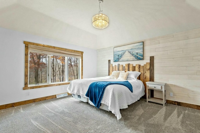 carpeted bedroom featuring a chandelier, vaulted ceiling, and wood walls