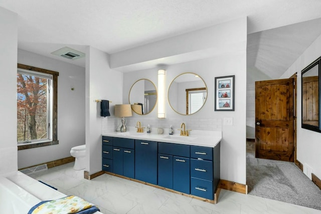 bathroom featuring vanity, decorative backsplash, and toilet