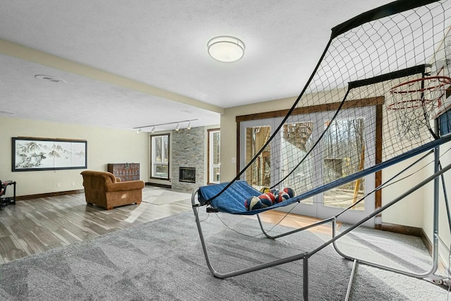 interior space with hardwood / wood-style flooring, a fireplace, rail lighting, and a textured ceiling