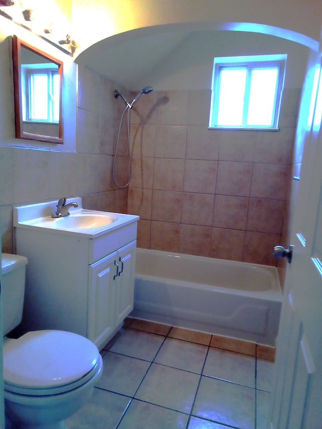 full bathroom with toilet, tiled shower / bath, tile walls, vanity, and tile patterned flooring