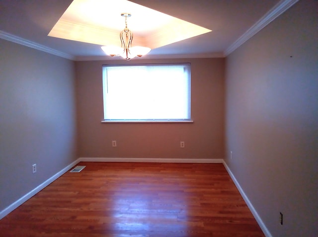 unfurnished room featuring dark wood-type flooring, a tray ceiling, and an inviting chandelier