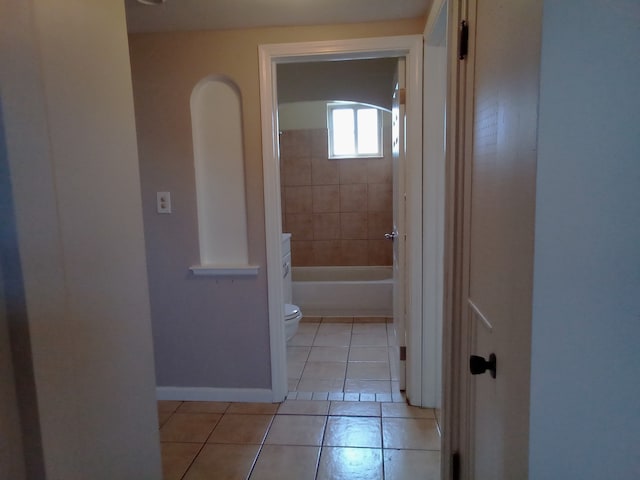 hallway featuring light tile patterned floors and baseboards