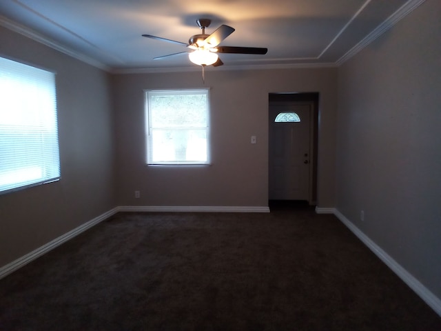 unfurnished room featuring dark colored carpet, ornamental molding, and ceiling fan