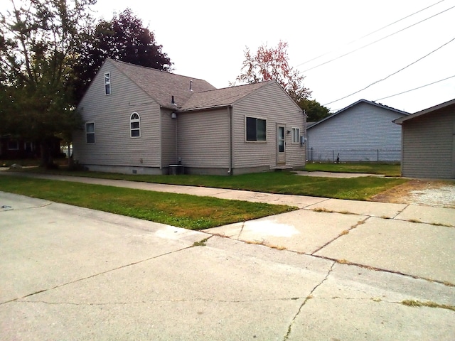 view of side of home with central air condition unit and a lawn