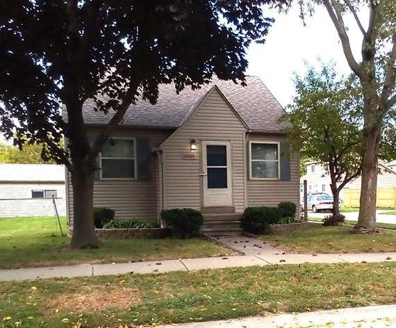 view of front of house with entry steps, a front yard, and roof with shingles
