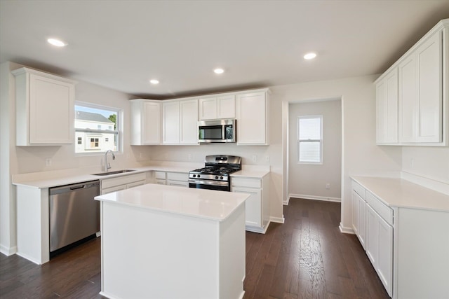 kitchen with a kitchen island, appliances with stainless steel finishes, sink, and white cabinets