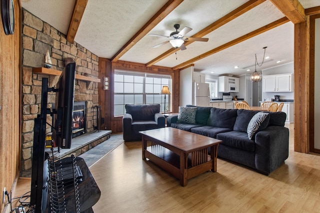 living room featuring vaulted ceiling with beams, light hardwood / wood-style flooring, and a textured ceiling