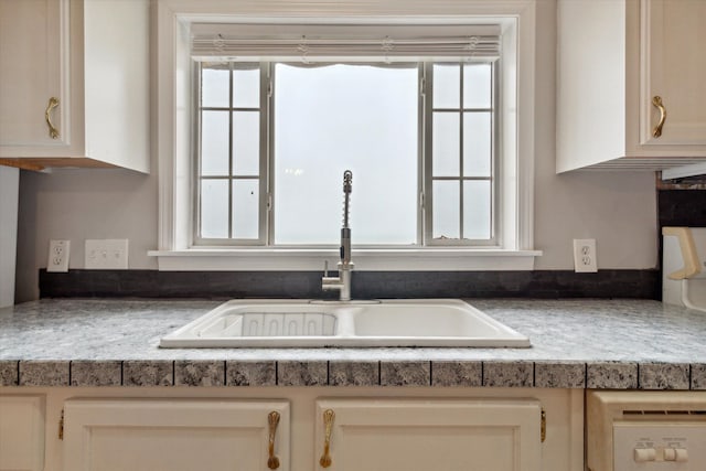 interior details with cream cabinets, dishwasher, and sink