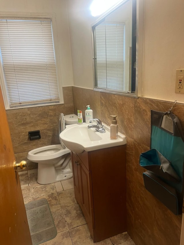 bathroom featuring tile patterned floors, vanity, toilet, and tile walls