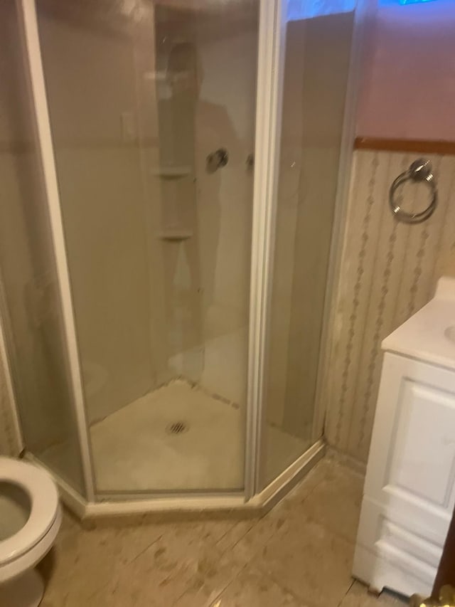 bathroom featuring tile patterned floors, toilet, a shower with door, and vanity