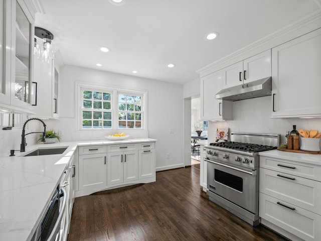 kitchen featuring decorative light fixtures, sink, white cabinets, high end range, and dark wood-type flooring