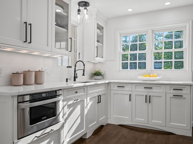 kitchen with dark wood-type flooring, sink, white cabinetry, decorative light fixtures, and decorative backsplash