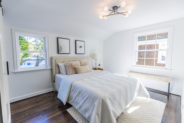 bedroom featuring dark wood-type flooring, a barn door, vaulted ceiling, and a notable chandelier