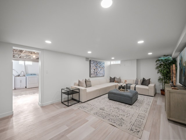 living room featuring washer / dryer, a healthy amount of sunlight, and light hardwood / wood-style flooring