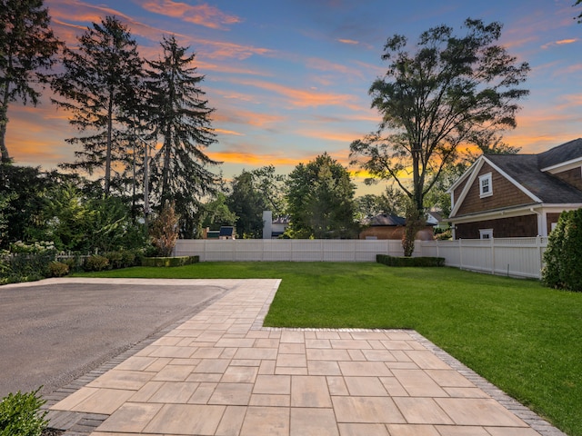 patio terrace at dusk featuring a lawn