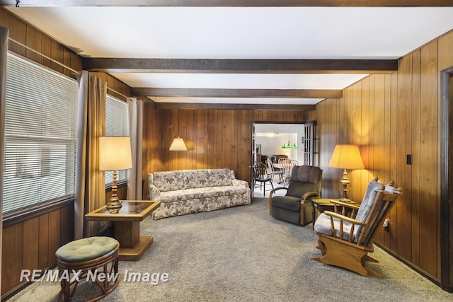 carpeted living room featuring plenty of natural light, beam ceiling, and wood walls