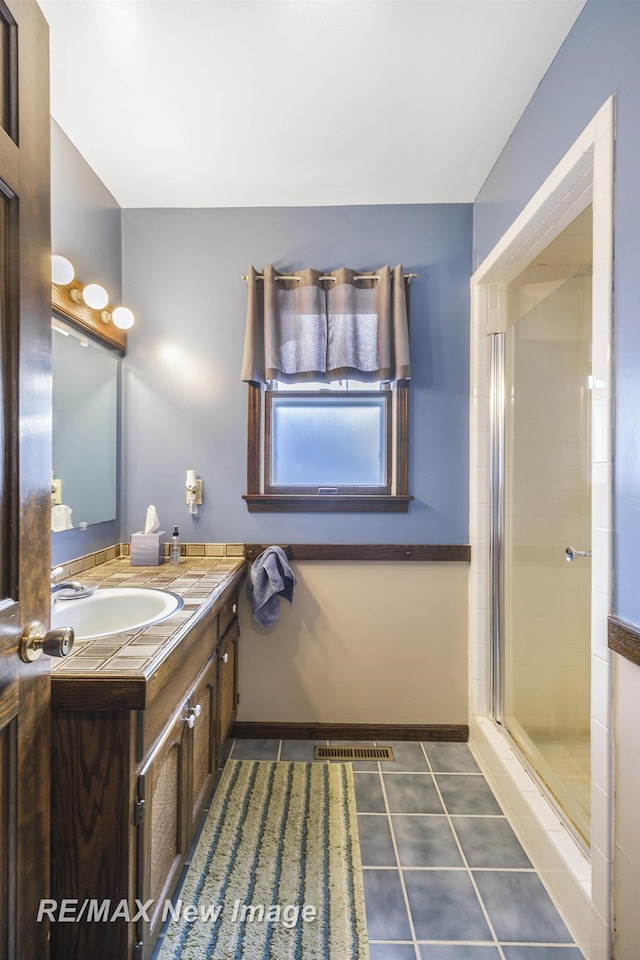 bathroom featuring tile patterned flooring, vanity, and a shower with shower door