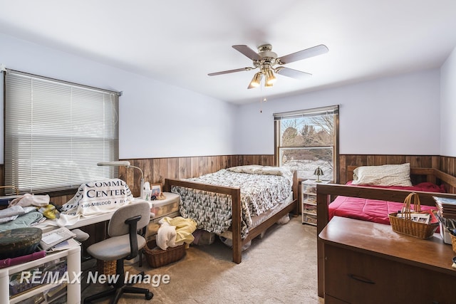 carpeted bedroom with ceiling fan and wooden walls