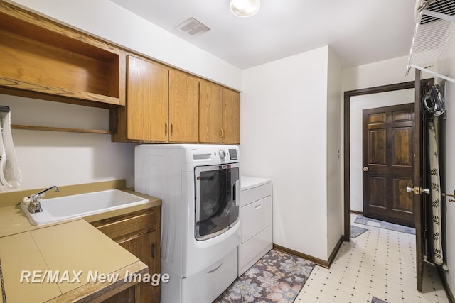 laundry room with separate washer and dryer, sink, and cabinets