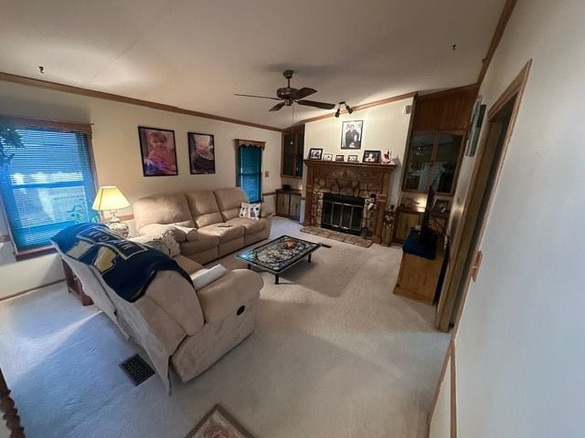 living room featuring light carpet, crown molding, a fireplace, and ceiling fan