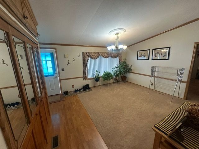 interior space with lofted ceiling, a notable chandelier, hardwood / wood-style flooring, and ornamental molding