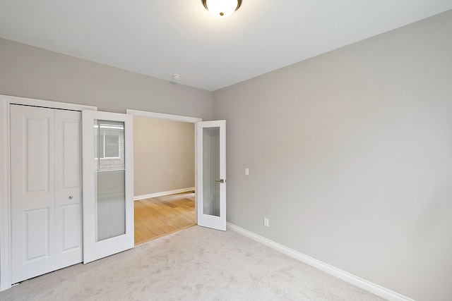 unfurnished bedroom with light carpet, a closet, and french doors