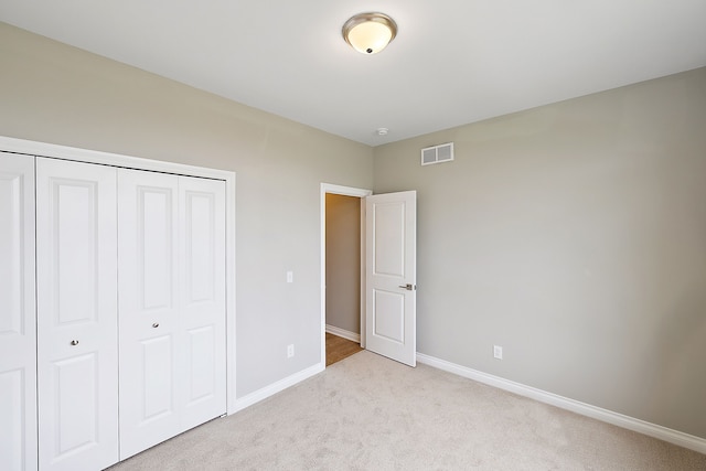 unfurnished bedroom featuring light colored carpet and a closet