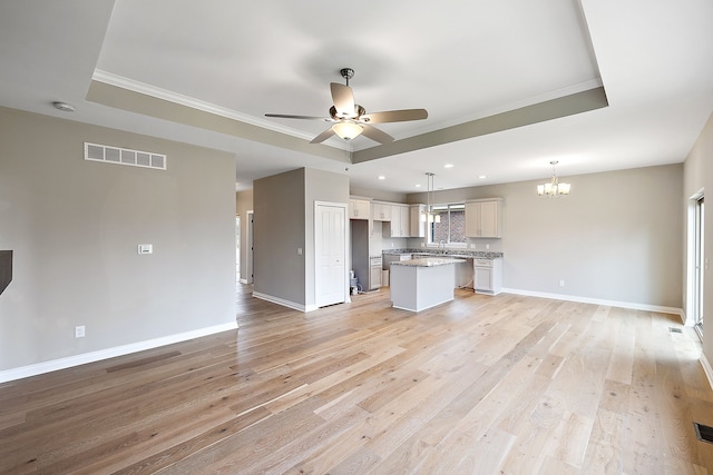 kitchen with a center island, light hardwood / wood-style flooring, a raised ceiling, pendant lighting, and ceiling fan with notable chandelier