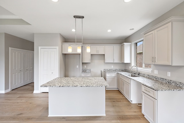 kitchen featuring sink, white cabinetry, a center island, light hardwood / wood-style flooring, and pendant lighting