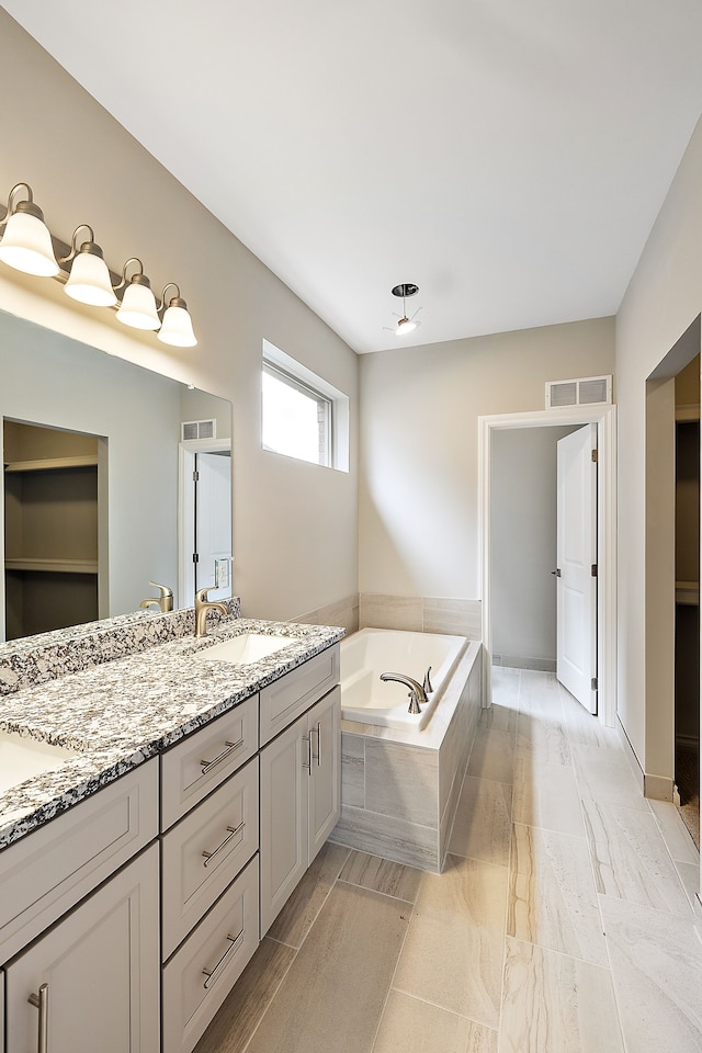 bathroom with vanity and tiled tub