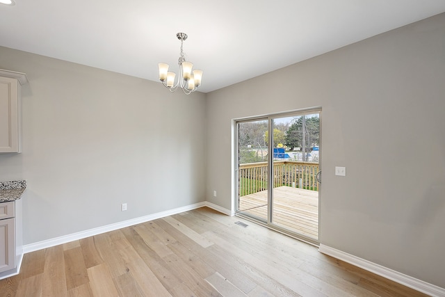 unfurnished dining area with an inviting chandelier and light hardwood / wood-style flooring