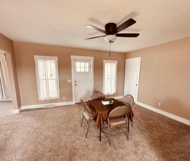 carpeted dining room featuring visible vents, ceiling fan, and baseboards