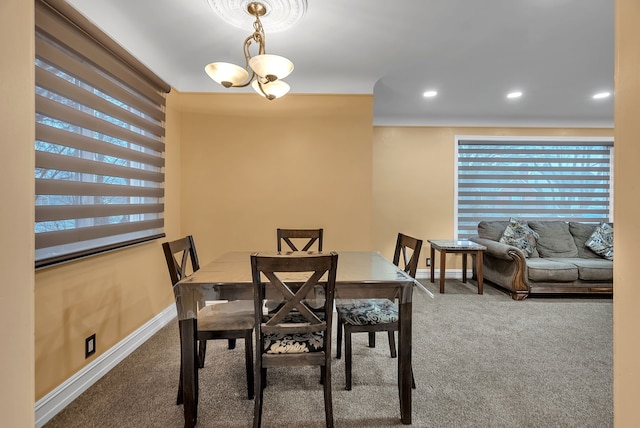 carpeted dining area with an inviting chandelier