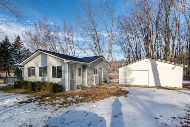 snow covered property featuring a garage, an outdoor structure, and central AC