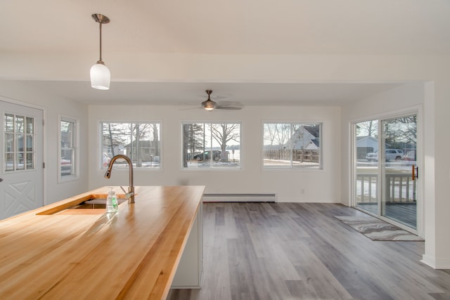 unfurnished dining area featuring baseboard heating, sink, and light wood-type flooring