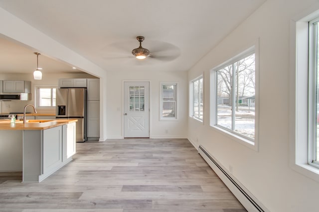 kitchen with butcher block countertops, baseboard heating, gray cabinetry, appliances with stainless steel finishes, and light wood-type flooring