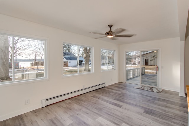 unfurnished sunroom featuring a baseboard heating unit and ceiling fan