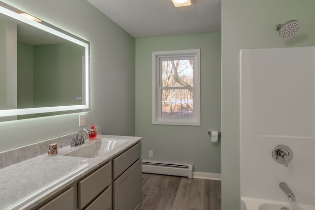 bathroom featuring a baseboard radiator, wood-type flooring, shower / washtub combination, and vanity