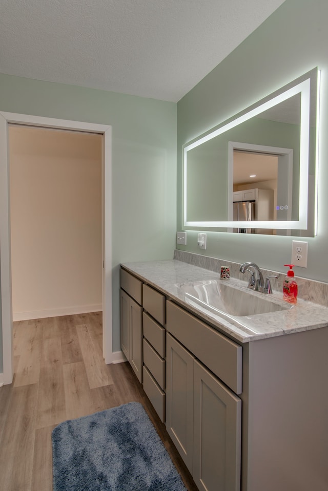 bathroom featuring vanity, wood-type flooring, and a textured ceiling