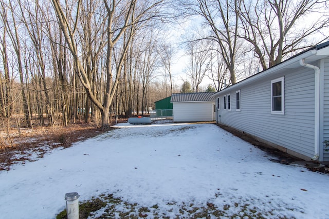 yard layered in snow featuring an outbuilding