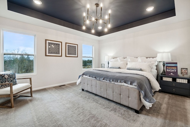 carpeted bedroom featuring a raised ceiling and a notable chandelier