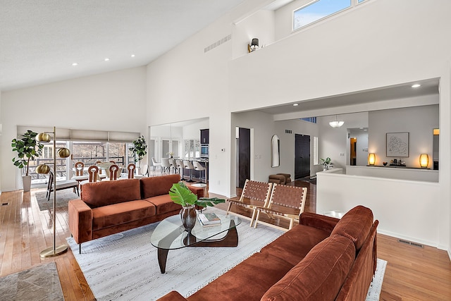 living area featuring a healthy amount of sunlight, light wood-type flooring, visible vents, and baseboards